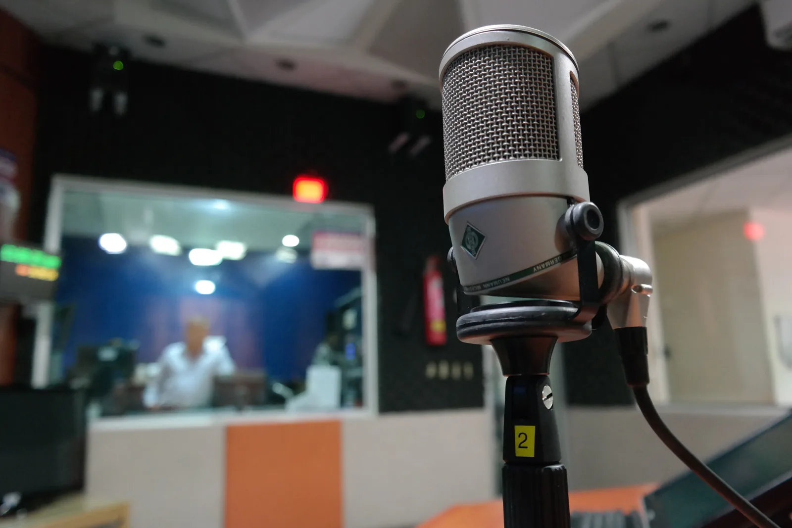 Broadcast microphone in the studio with an engineer at the board